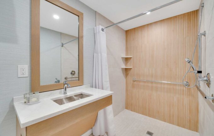 Bathroom vanity and shower in the ADA Accessible Hotel Room with Roll in Shower and Kitchenette at Mahalo Cape May beachfront hotel in Cape May, NJ