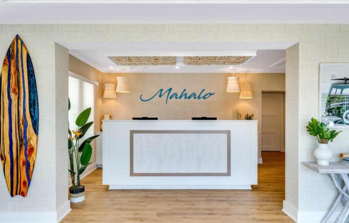 Mahalo Cape May New Beachfront hotel in Cape May NJ Lobby with wooden surfboard art Mahalo sign and front desk with other decor on the side
