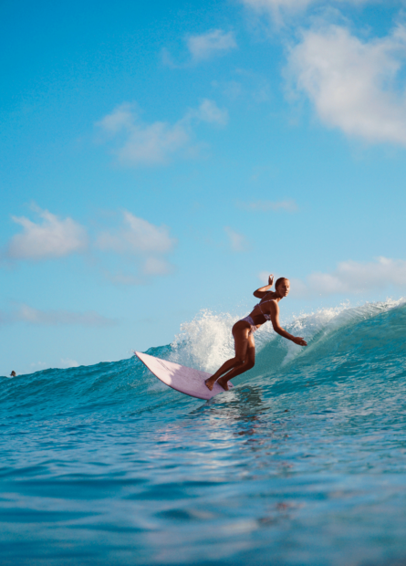 Woman surfing the waves on a pink surfboard near our Wildwood Crest hotel