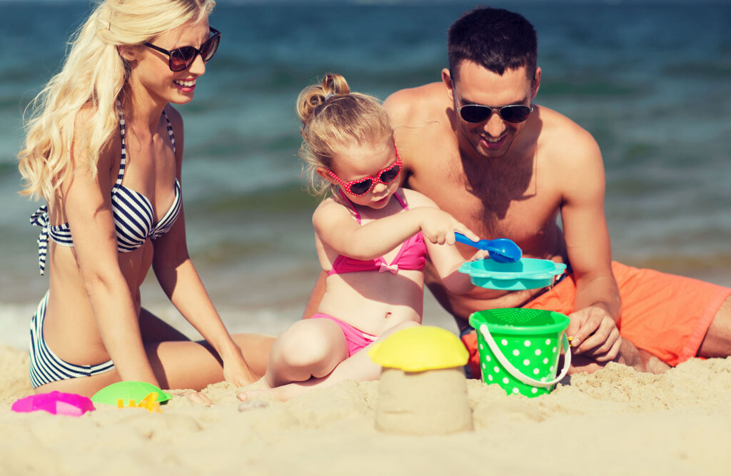 happy family playing with sand toys on beach