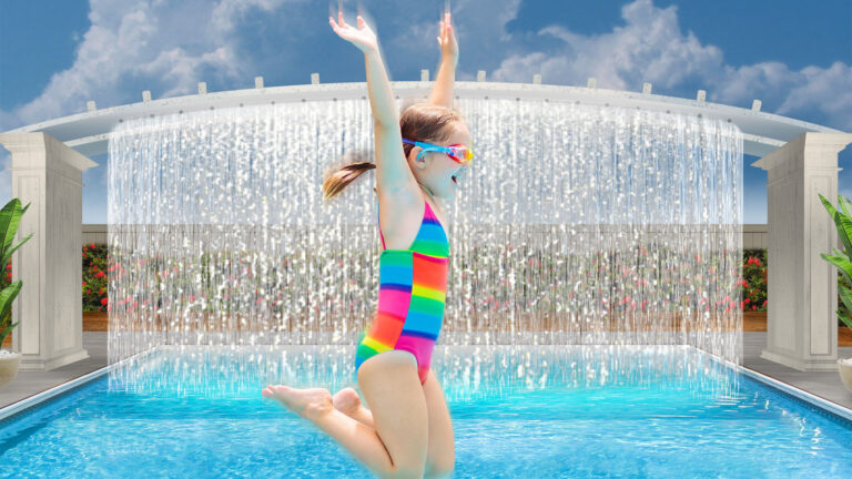 Young girl in a rainbow bathing suit jumping into the resort pool in front of a cascading waterfall.