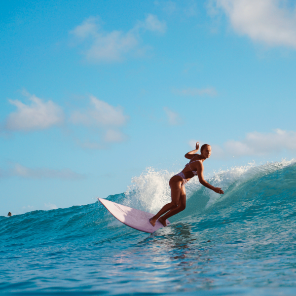 Woman surfing the waves on a pink surfboard near our Wildwood Crest hotel