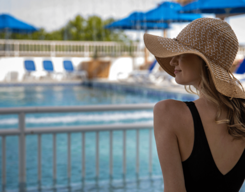 Woman is a sunhat sitting by the pool