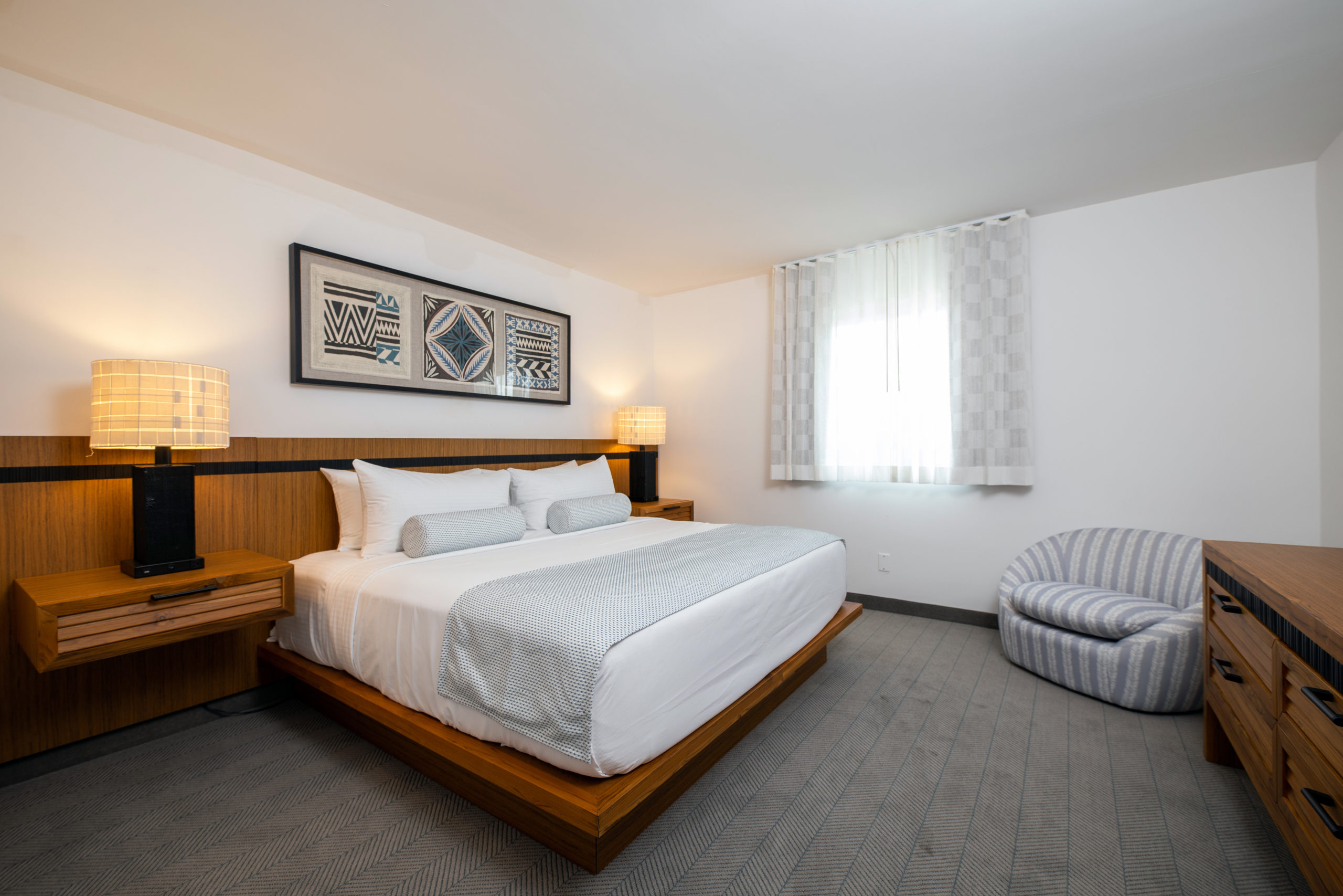 Signature Mahalo Suite with brown wooden platform bed and island artwork at our Diamond Beach hotel