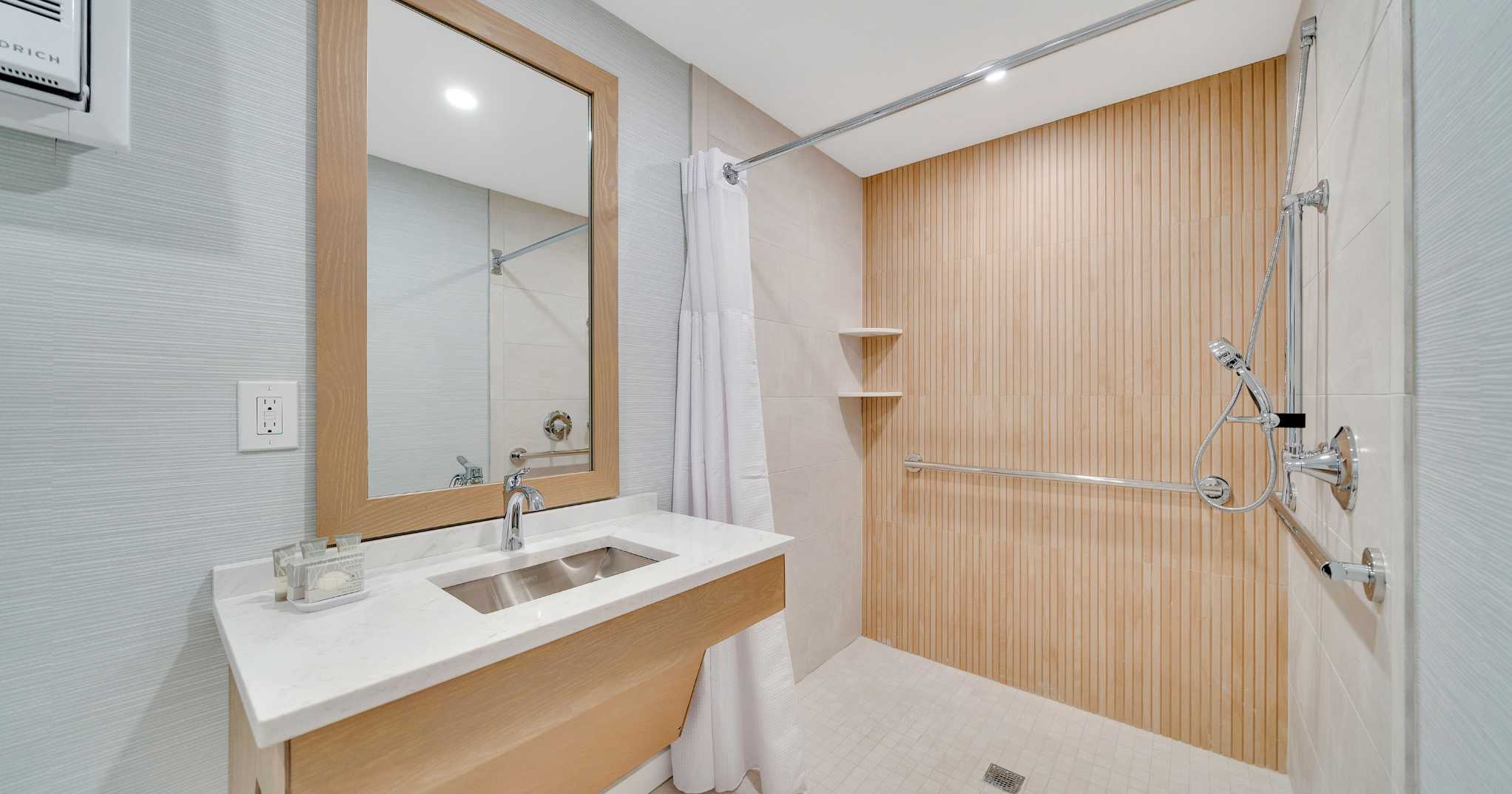 Bathroom vanity and shower in the ADA Accessible Hotel Room with Roll in Shower and Kitchenette at Mahalo Cape May beachfront hotel in Cape May, NJ