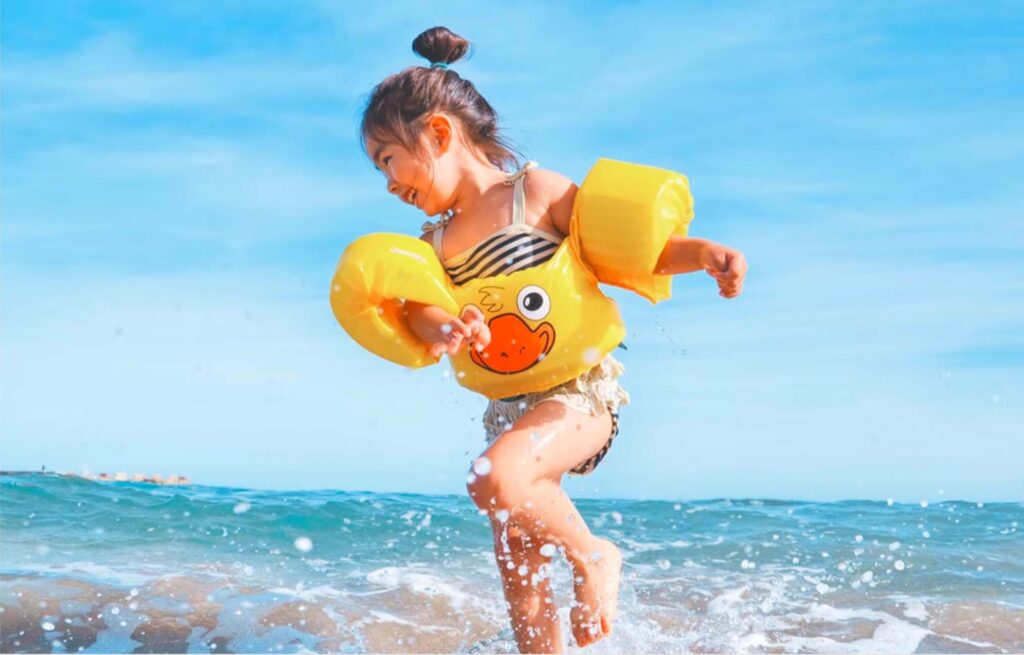 Little girl in floaties playing in the ocean
