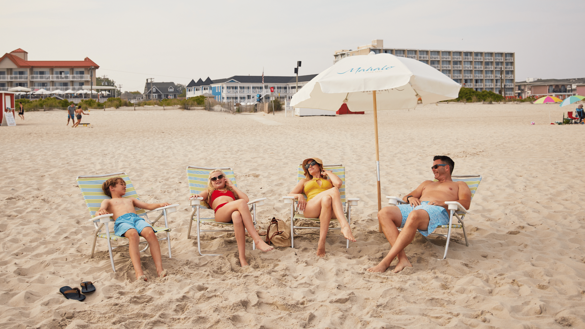 Family lounging on the beach in front of a hotel on Cape May beach