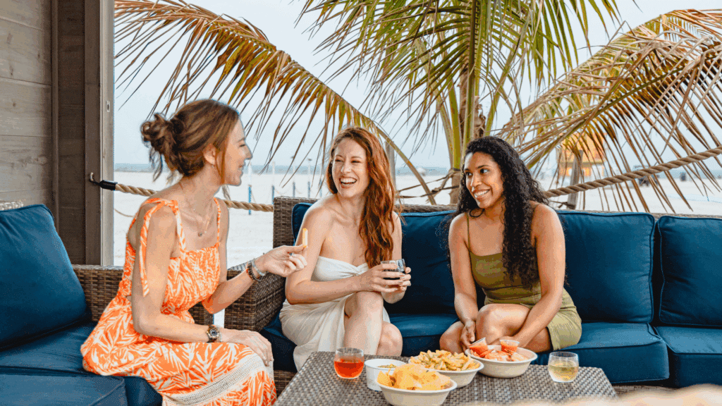 Three women enjoying drinks in food in a cabana at the Star Beach Bar in Wildwood