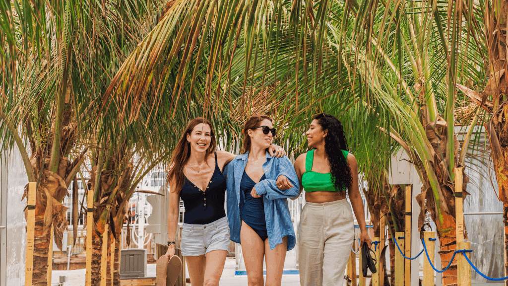 Three women walking down the palm tree tunnel at ICONA Diamond Beach in Wildwood
